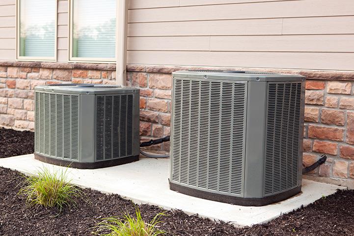 two air conditioner units along a building wall